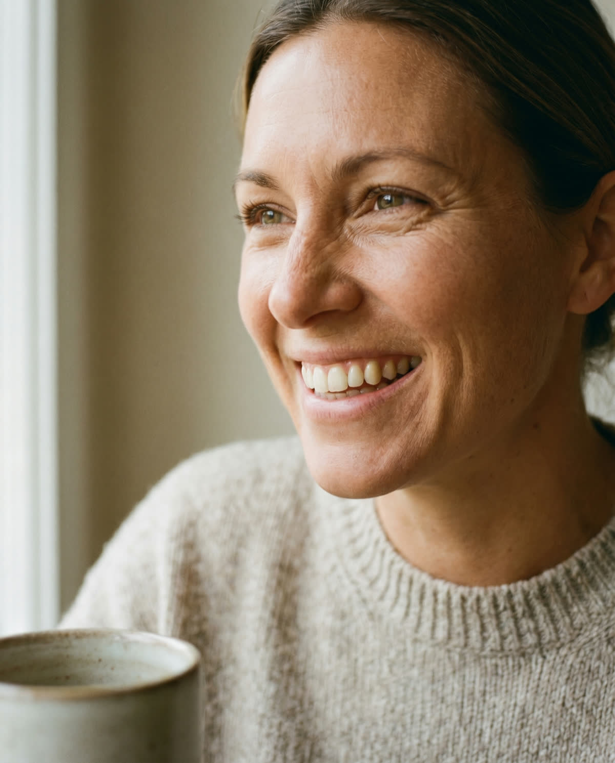 Paciente sorrindo com naturalidade perto de uma janela